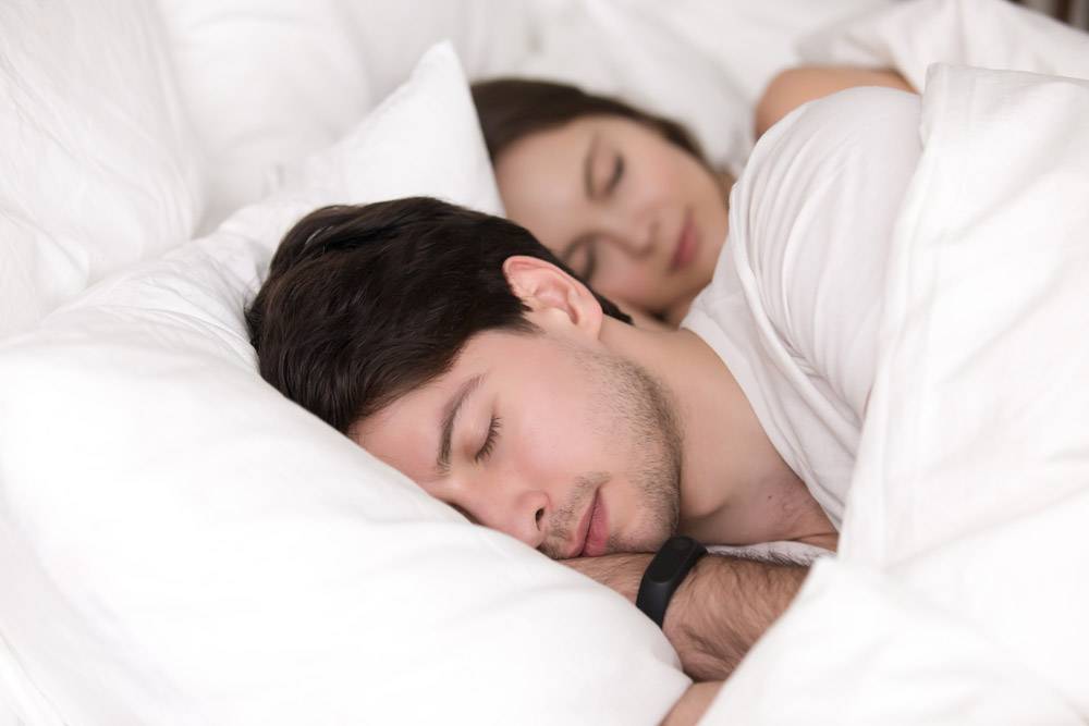 年轻夫妇在床上睡觉男人戴着智能手表跟踪_3955550