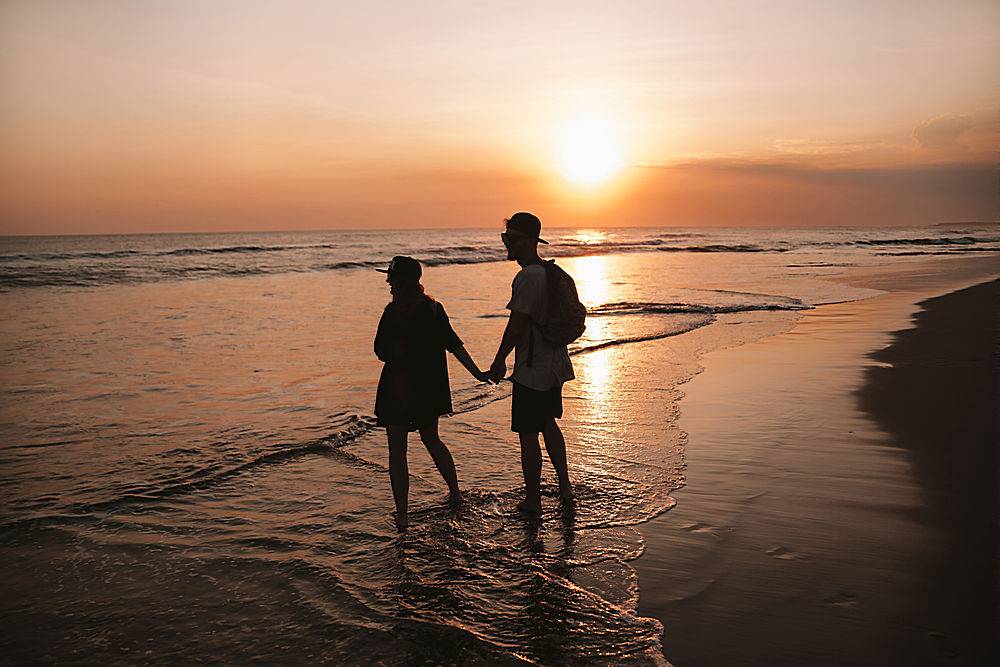 年轻浪漫情侣走在海滩上的剪影肖像女孩和_8270051