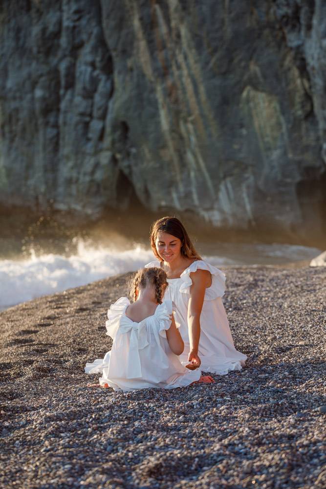 日落时分幸福的母女俩身着白裙坐在海边_9178947
