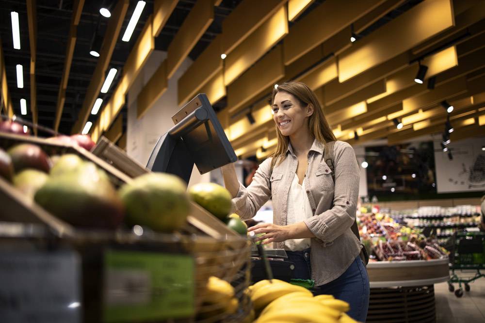 超市的妇女使用自助数字标度来测量水果的重